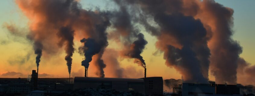 Rauchende Fabrikschlote vor Abendhimmel